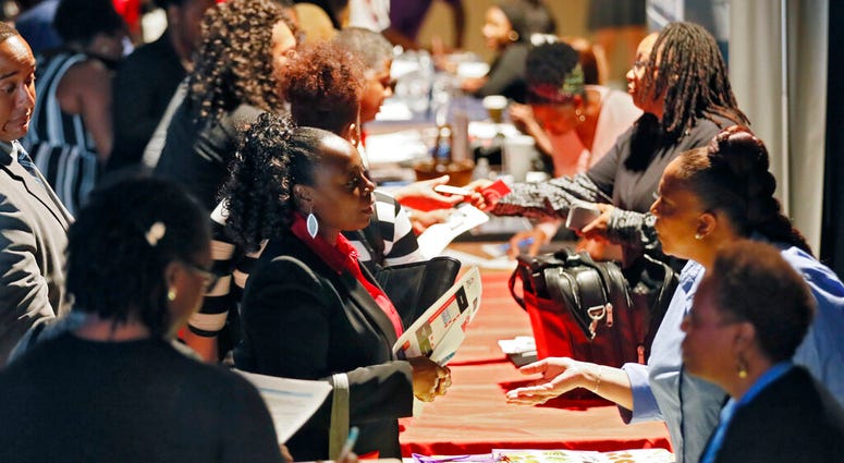 FILE - In this Aug. 14, 2019, file photo company representatives from Verizon, Goodwill, Kaiser Permanente and UPS, right, talk with potential applicants during a job and resource fair in Atlanta.