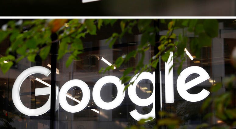 his combo of photo shows the General Motors logo on May 16, 2014, at the company's world headquarters in Detroit, top, and the Google logo at their offices in Granary Square, London on Nov. 1, 2018, bottom.
