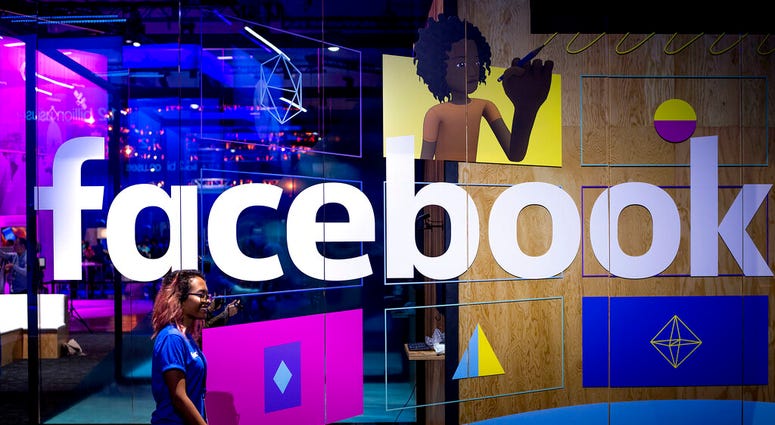 FILE - In this Tuesday, April 18, 2017, file photo, a conference worker passes a demo booth at Facebook's annual F8 developer conference, in San Jose, Calif. New York Attorney General Letitia James says a bipartisan coalition of state attorneys general is