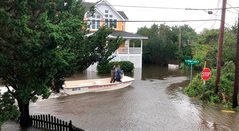 Ocracoke Volunteer Fire Department chief Albert O’Neal, in blue shirt, boats down Sunset Drive on his way to seek out islanders stranded in their flooded homes in the aftermath of Hurricane.