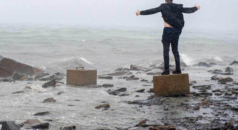 An unidentified man raises his arms in the winds from Hurricane Dorian along the Halifax harbor in Dartmouth, Nova Scotia, Canada, on Saturday, Sept. 7, 2019. (Andrew Vaughan/The Canadian Press via AP)