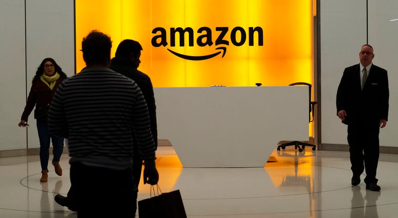 FILE - In this Feb. 14, 2019, file photo people walk into the lobby for Amazon offices in New York. The online shopping giant is holding job fairs across the country next week, aiming to hire more than 30,000 people by early next year, a 5% bump in its to