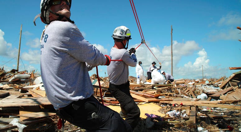 Members of the fire rescue team Task Force 8, from Gainesville, Florida, help remove a body one week after Hurricane Dorian hit The Mudd neighborhood in the Marsh Harbor area of Abaco Island, Bahamas, Monday, Sept. 9, 2019.