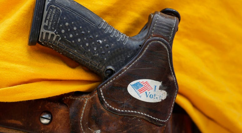 FILE - In this April 14, 2018 file photo, a man wears an unloaded pistol during a pro gun-rights rally in Austin, Texas.