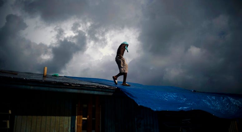 Trevon Laing walks the roof of his house to repair the damage made by Hurricane Dorian, in Gold Rock Creek, Grand Bahama, Bahamas, Thursday Sept. 12, 2019. (AP Photo / Ramon Espinosa)