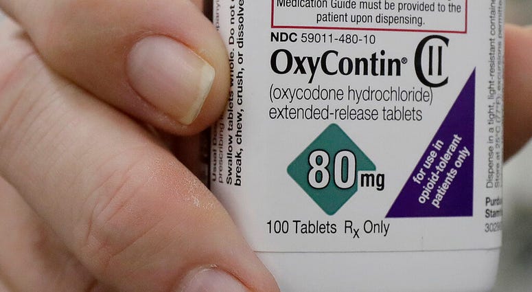In this April 2, 2018, file photo, a pharmacist in San Francisco poses for photos holding a bottle of OxyContin. (AP Photo/Jeff Chiu, File)