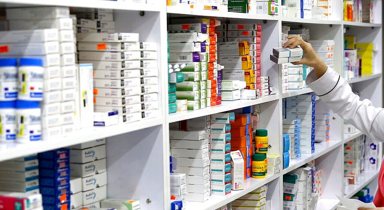 FILE - In this Nov. 5, 2018 file photo, a drugstore employee reaches for medicine from shelf in downtown Tehran, Iran. A cheap, daily pill that combines four drugs has been tested for the first time in the United States to see if it works as well among lo