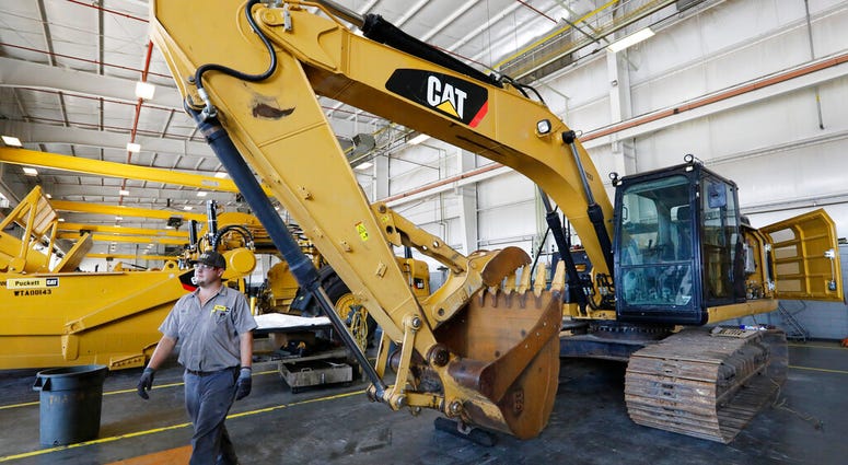 In this Sept. 18, 2019, photo a Puckett Machinery Company technician walks past a new heavy duty Caterpillar excavator that awaits modification at Puckett Machinery Company in Flowood, Miss.