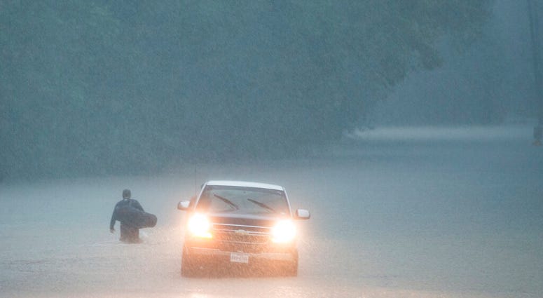 A man walks into high water into his neighborhood as rain from Tropical Depression Imelda inundated the area on Thursday, Sept. 19, 2019, near Patton Village, Texas. (Brett Coomer/Houston Chronicle via AP)