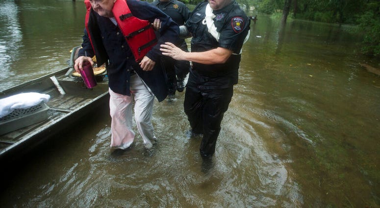 Fred Stewart, left, is helped to high ground after he was rescued from his flooded neighborhood as rains from Tropical Depression Imelda inundated the area, Thursday, Sept. 19, 2019, in Splendora, Texas. (Brett Coomer/Houston Chronicle via AP)