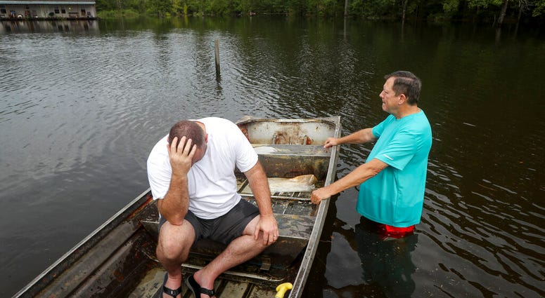 Stephen Gilbert, left, and his father-in-law sit in front of their flooded property on Friday, Sept. 20, 2019, in the Mauriceville, Texas, area.