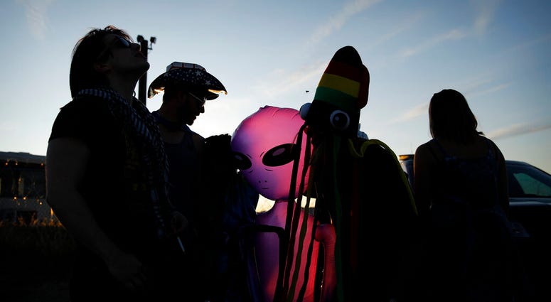 People stand around an inflatable alien at an entrance to the Nevada Test and Training Range near Area 51, Friday, Sept. 20, 2019, near Rachel, Nev. People came to visit the gate inspired by the "Storm Area 51" internet hoax.