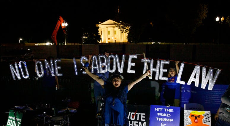 rotesters with Kremlin Annex with a light sign that reads "NO ONE IS ABOVE THE LAW" call to impeach President Donald Trump in Lafayette Square Park in front of the White House in Washington, Thursday, Sept. 26, 2019.