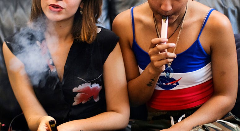 FILE - In this Saturday, June 8, 2019 file photo, two women smoke cannabis vape pens at a party in Los Angeles.