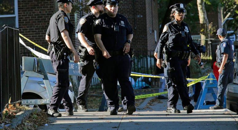 Emergency personnel walk near the scene of a fatal shooting of a New York City police officer in the Bronx borough of New York, Sunday, Sept. 29, 2019. (AP Photo/Seth Wenig)