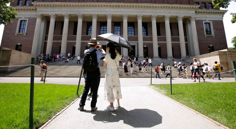 FILE - In this July 16, 2019, file photo, people stop to record images of Widener Library on the campus of Harvard University in Cambridge, Mass.