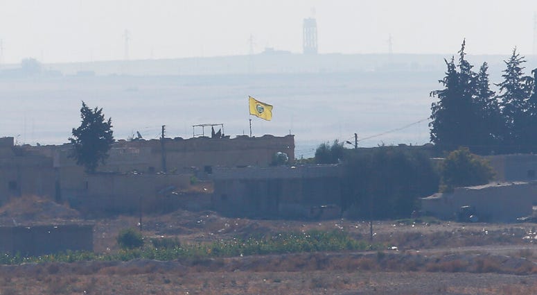 A flag of Kurdish People's Protection Units, or YPG, flies on a building in the Syrian town of Tel Abyad, Tuesday, Oct. 8, 2019. (AP Photo/Lefteris Pitarakis)