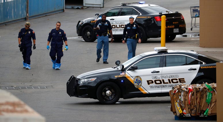 In this Tuesday, Aug. 6, 2019 file photo, police officers walk behind a Walmart at the scene of a mass shooting at a shopping complex, in El Paso, Texas. (AP Photo/John Locher, File)