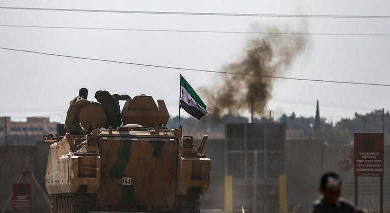 Turkish-backed Syrian opposition fighters on an armoured personnel carrier drive to cross the border into Syria, in Akcakale, Sanliurfa province, southeastern Turkey, Friday, Oct. 18, 2019. (AP Photo/Emrah Gurel)