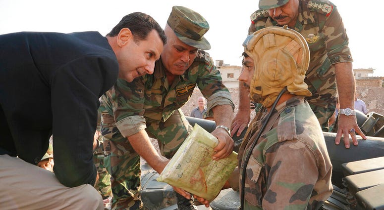In this photo released on the official Facebook page of the Syrian Presidency, Syrian President Bashar Assad, left, speaks with Syrian troops during his visit to the strategic town of Habeet, in the northwestern province of Idlib, Syria. (Facebook page of In this photo released on the official Facebook page of the Syrian Presidency, Syrian President Bashar Assad, left, speaks with Syrian troops during his visit to the strategic town of Habeet, in the northwestern province of Idlib, Syria. (Facebook page of
