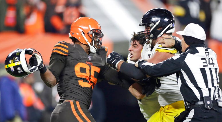 Cleveland Browns defensive end Myles Garrett, left, gets ready to hit Pittsburgh Steelers quarterback Mason Rudolph, second from left, with a helmet during the second half of an NFL football game Nov. 14, 2019, in Cleveland. (AP Photo/Ron Schwane)