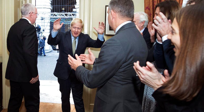 Britain's Prime Minister Boris Johnson is greeted by staff as he returns to 10 Downing Street, London, after meeting Queen Elizabeth II and accepting her invitation to form a new government, Friday Dec. 13, 2019. (Stefan Rousseau/PA via AP) Britain's Prime Minister Boris Johnson is greeted by staff as he returns to 10 Downing Street, London, after meeting Queen Elizabeth II and accepting her invitation to form a new government, Friday Dec. 13, 2019. (Stefan Rousseau/PA via AP)