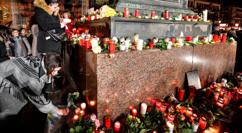 People place candles and flowers at a monument on the market place during a mourning for the victims of the shooting in Hanau, Germany, Thursday, Feb. 20, 2020. (AP Photo/Martin Meissner) People place candles and flowers at a monument on the market place during a mourning for the victims of the shooting in Hanau, Germany, Thursday, Feb. 20, 2020. (AP Photo/Martin Meissner)