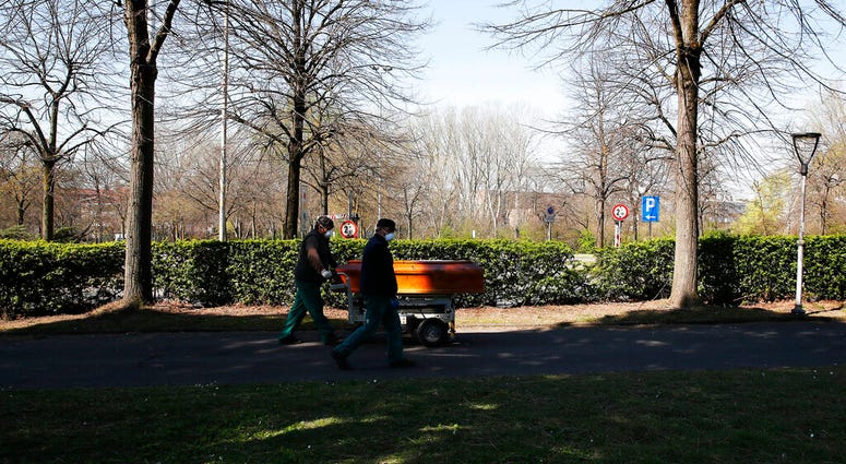 Two men carry a coffin to the Melegnano cemetery's morgue, outskirts of Milan, Italy, Tuesday, March 24, 2020. (AP Photo/Antonio Calanni) Two men carry a coffin to the Melegnano cemetery's morgue, outskirts of Milan, Italy, Tuesday, March 24, 2020. (AP Photo/Antonio Calanni)