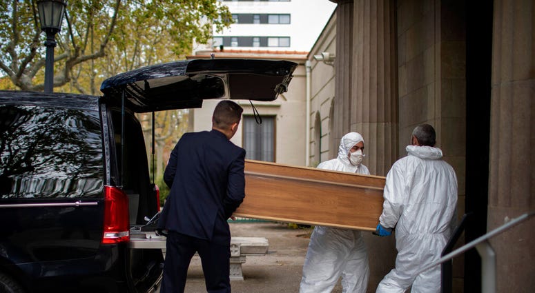 Undertakers carry a coffin for a burial at a Barcelona cemetery during the coronavirus outbreak, Spain, Friday, March 27, 2020.