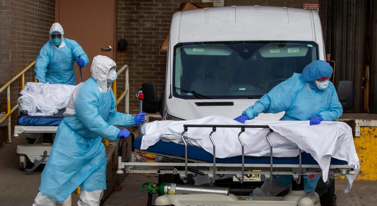 Medical personnel wearing personal protective equipment remove bodies from the Wyckoff Heights Medical Center Thursday, April 2, 2020 in the Brooklyn borough of New York.