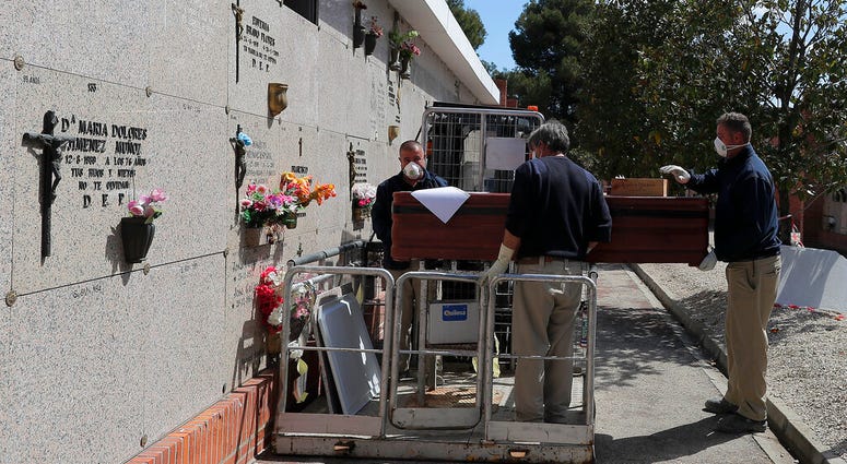 Undertakers carry the coffin of Rafael Catalan Villasanti, 83, during the coronavirus outbreak at the Carabanchel cemetery in Madrid, Spain, Saturday, April 4, 2020.
