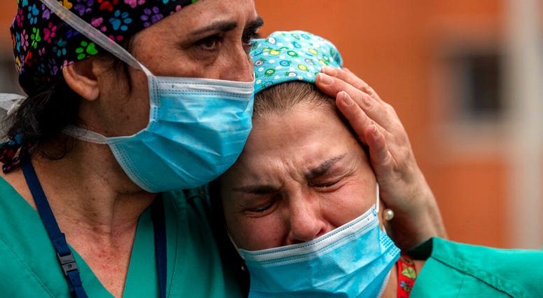 Health workers cry during a memorial for their co-worker Esteban, a male nurse that died of the coronavirus disease, at the Severo Ochoa Hospital in Leganes in Leganes, Spain, Friday, April 10, 2020.