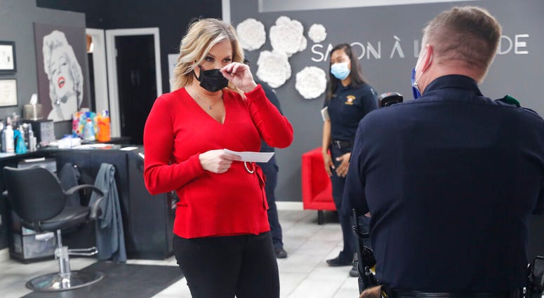 Salon owner Shelley Luther holds a citation and speaks with a Dallas police officer after she was cited for reopening her Salon A la Mode in Dallas, Friday, April 24, 2020.