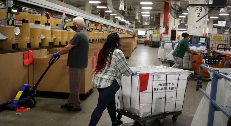 Postal workers wear masks and gloves during the coronavirus pandemic as they physically distance from each other at the United States Postal Service processing and distribution center on Thursday, April 30, 2020, in Oakland, Calif.