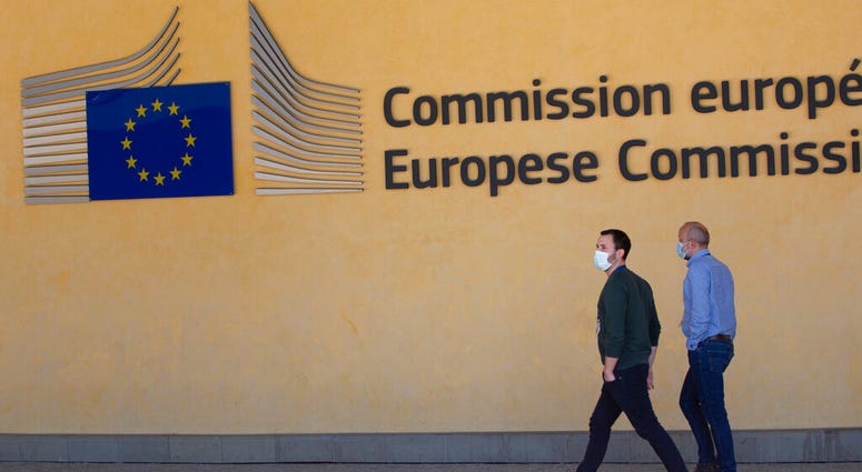Two men walk, wearing mouth masks to prevent against the spread of the coronavirus, COVID-19, outside EU headquarters in Brussels, Thursday, May 7, 2020.