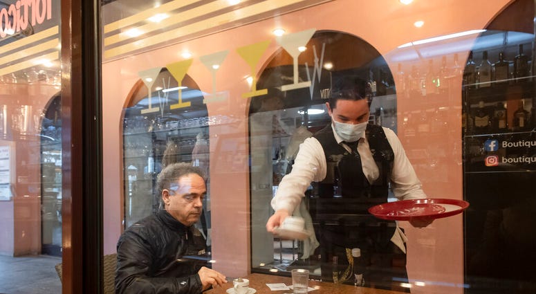 A waiter is serving a coffee to a guest at the restaurant Portico on the Piazza Grande in Locarno, Switzerland, Monday, May 11, 2020.