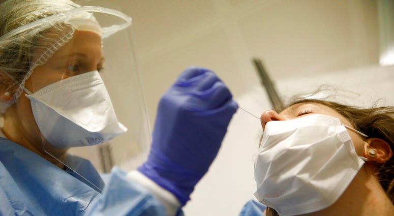 A health-care worker collects a swab sample to be tested with the Coronavirus at the European Parliament in Strasbourg, eastern France, Tuesday, May 12, 2020.