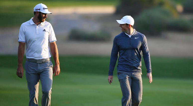 FILE - In this Jan. 18, 2018, file photo, Dustin Johnson of the United States, left, and Rory McIlroy of Northern Ireland talk on the 10th fairway during the first round of the Abu Dhabi Championship golf tournament in Abu Dhabi, United Arab Emirates.