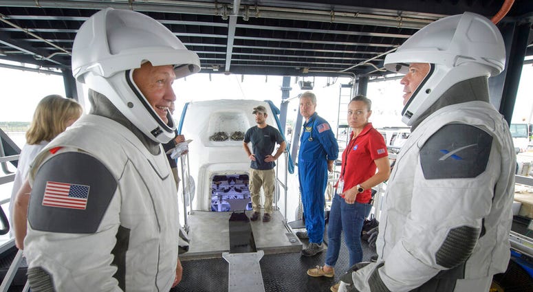 FILE - In this Aug. 13, 2019 file photo, NASA astronauts Doug Hurley, left, and Bob Behnken work with teams from NASA and SpaceX to rehearse crew extraction from SpaceX's Crew Dragon, which will be used to carry humans to the International Space Station,