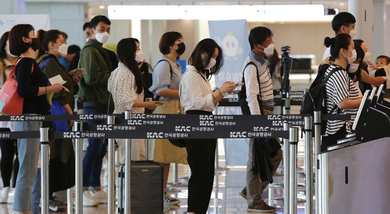 Passengers wearing face masks line up to board their planes at the domestic flight terminal of Gimpo airport in Seoul, South Korea, Wednesday, May 27, 2020.
