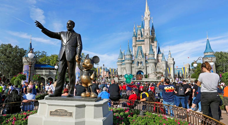 FILE - In this Jan. 9, 2019 photo, guests watch a show near a statue of Walt Disney and Micky Mouse in front of the Cinderella Castle at the Magic Kingdom at Walt Disney World in Lake Buena Vista, part of the Orlando area in Fla.