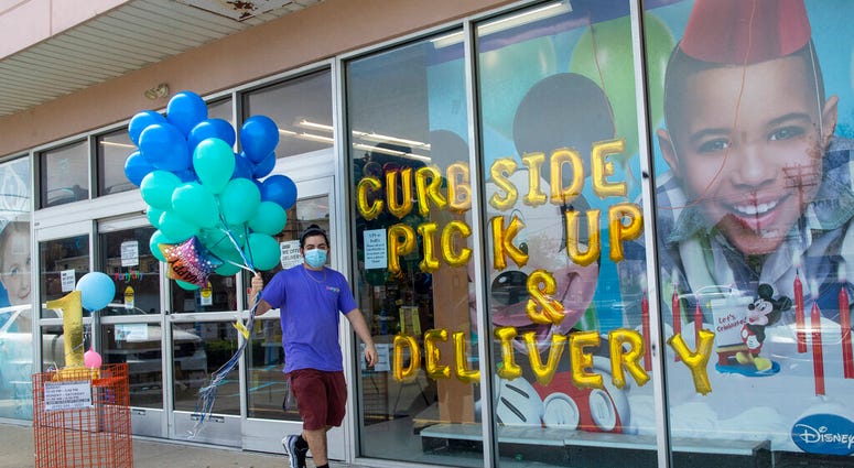 A Party City employee delivers balloons to a customer curbside, Wednesday, May 27, 2020, in Oceanside, N.Y. Long Island has become the latest region of New York to begin easing restrictions put in place to curb the spread of the coronavirus as it enters t