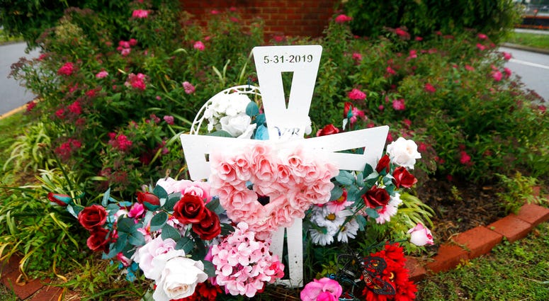 In this May 22, 2020, photo, a group of flowers and a cross mark the entrance to Jason Nixon's neighborhood in Virginia Beach, Va. The flowers are a memorial to Kate Nixon who was killed in last year's shootings at a Virginia Beach municipal building.