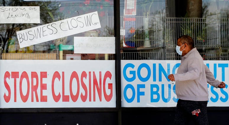 FILE - In this May 21, 2020 file photo, a man looks at signs of a closed store due to COVID-19 in Niles, Ill.
