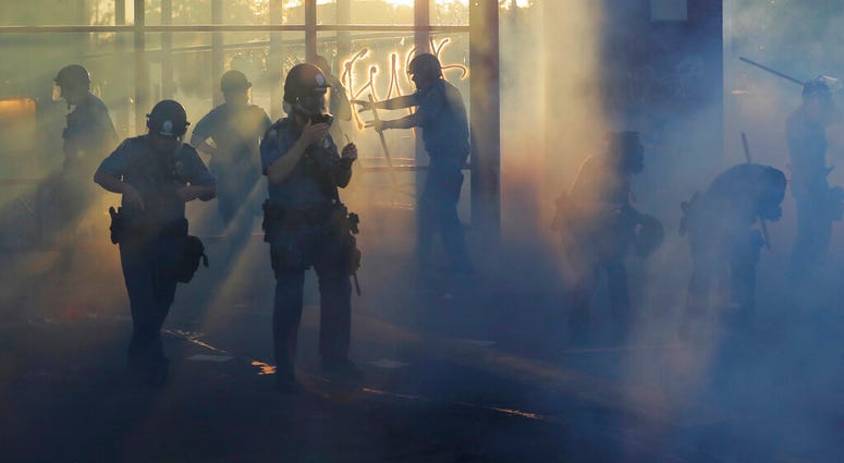 Police move through an area during demonstrations Thursday, May 28, 2020, in St. Paul, Minn. Protests over the death of George Floyd, the black man who died in police custody broke out in Minneapolis for a third straight night.
