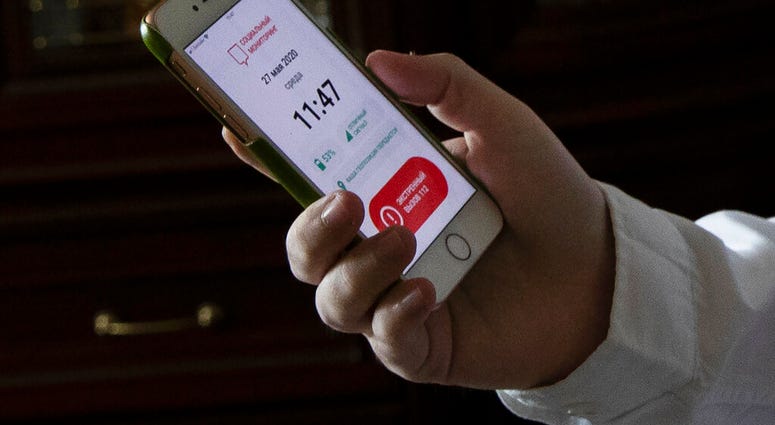 In this May 27, 2020, photo, Vladimir Perevalov shows a Social Monitoring app installed on his smartphone in his apartment in Shcherbinka, outside Moscow, Russia.