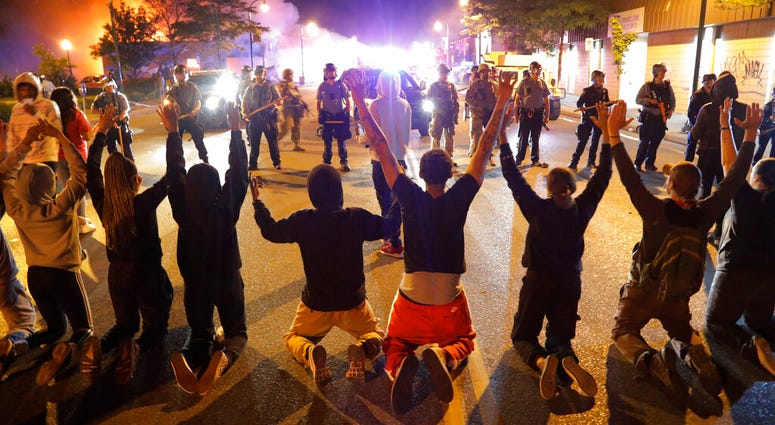 Demonstrators kneel before police Saturday, May 30, 2020, in Minneapolis. Protests continued following the death of George Floyd, who died after being restrained by Minneapolis police officers on Memorial Day.
