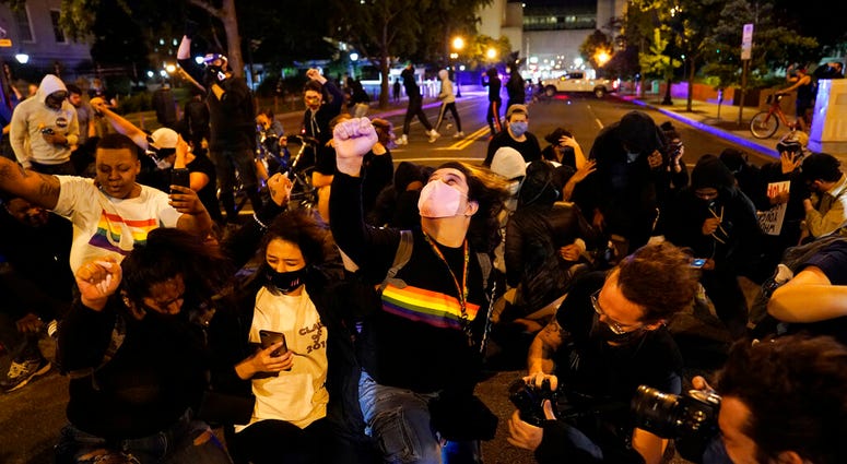A helicopter circles low as demonstrators kneel to protest the death of George Floyd, Monday, June 1, 2020, near the White House in Washington.