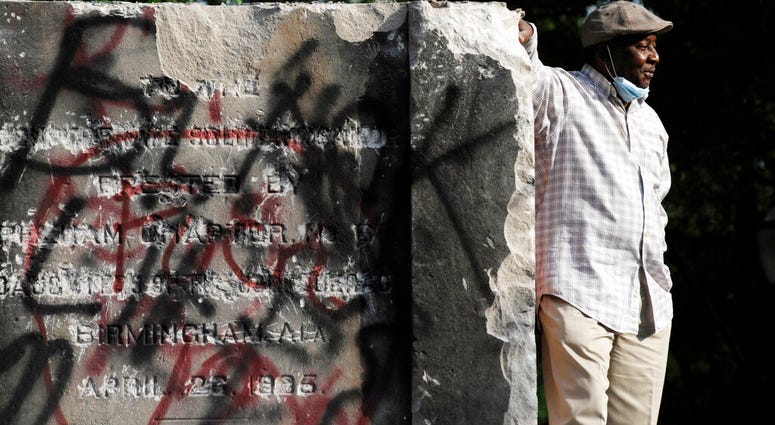 Robert Walker poses for a photograph on the remains of a Confederate memorial that was removed overnight in Birmingham, Ala., on Tuesday, June 2, 2020.