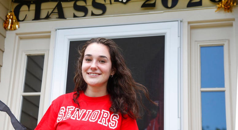 In this June 1, 2020 photo, high school graduate Lizzie Quinlivan poses at her home in Hingham, Mass.